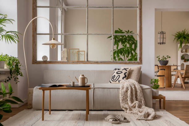 istock Interior design of open space interior with modular sofa, big window, stylish lamp, wooden coffee table, round table, rattan chair, pillows, plants and personal accessories. Home decor. Template. 1470504931