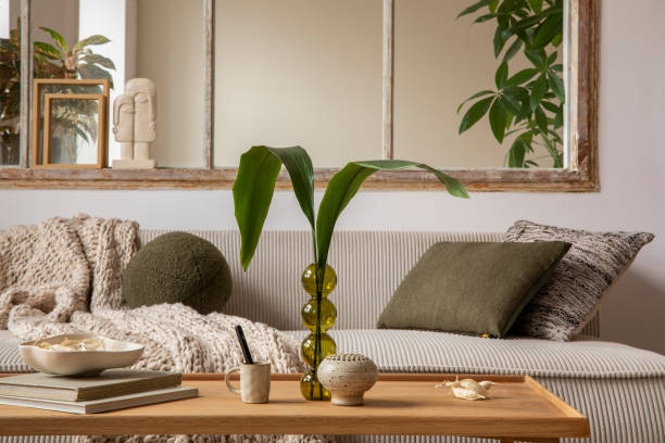 istock Aesthetics composition of open space interior with modular sofa, wooden coffee table, cup window, braided plaid, books, bowl, glass vase with leaves and personal accessories. Home decor. Template. 1470504986