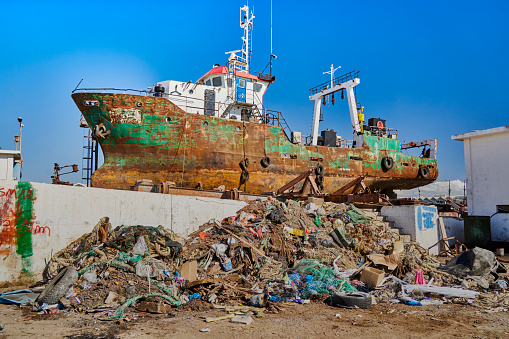 Mahdia, Tunesia, January 29, 2023: Rusty ship stands behind a pile of rubbish for repair work in the port dry dock