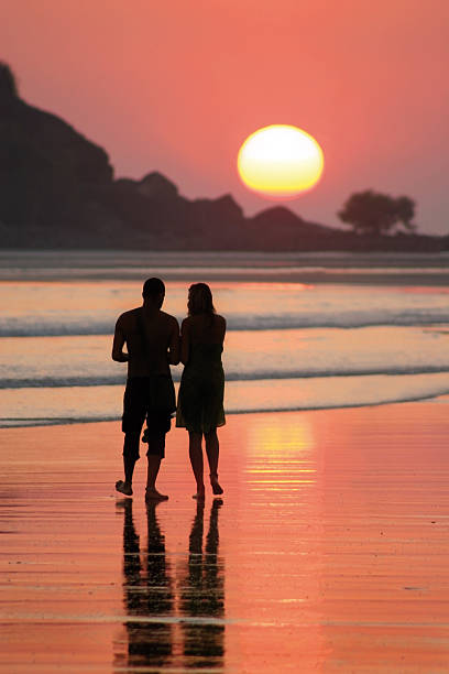 couple and sunset couple go for a walk on Palolem beach on sunset palolem beach stock pictures, royalty-free photos & images