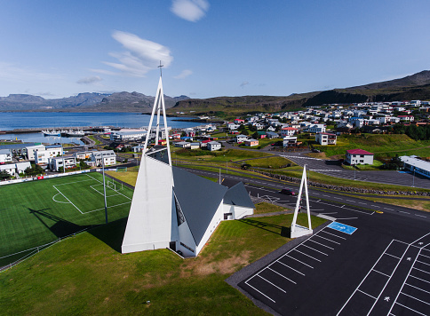 View of the tiny town Olafsvik in Iceland with a futuristic church and football field in the foreground