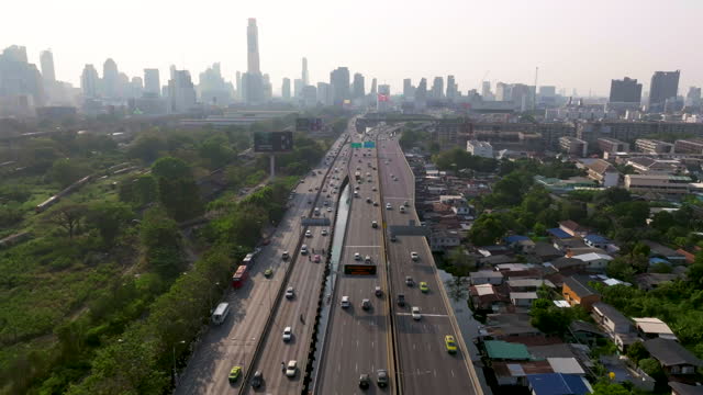 Aerial view of elevated expressway running into Bangkok's business district in the evening. The traffic is congested during rush hour.