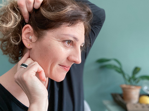 Smiling woman showing her correctly placed hearing aid