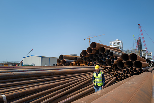 A male worker walks on the steel pipe at the chemical plant site