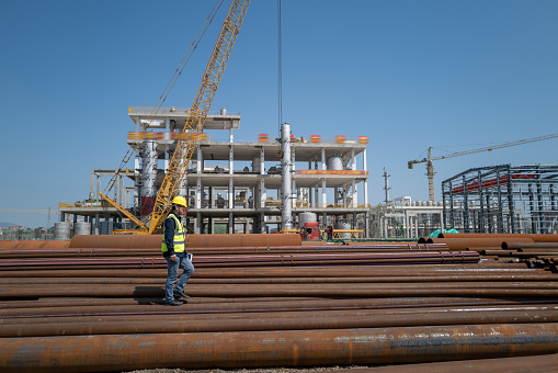 A male worker walks on the steel pipe at the chemical plant site