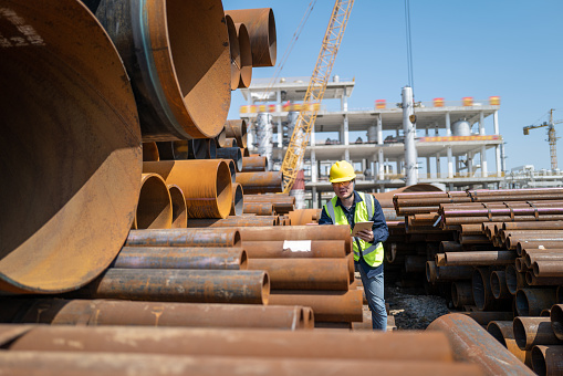 A male worker checks the quality of steel pipes on the construction site