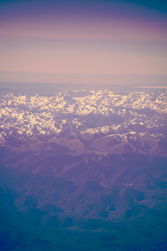 Mountain peaks covered in snow. Natural background from above in purple psychedelic colors. Pyrenees mountain chain. Vertical orientation.