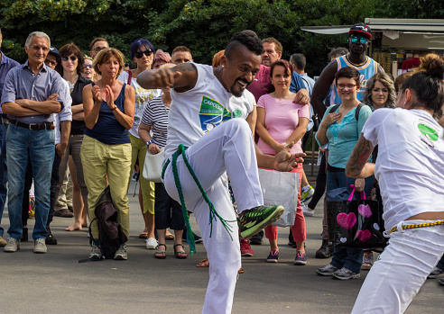 Milan 04/06/2017 joyful black dancer performs a capoeira with a white girl in front of an audience in a city square