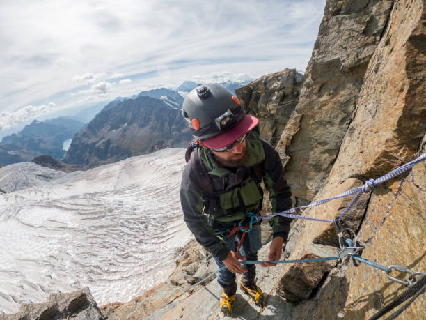 istock Mountaineer on rock face ascending summit 1470516433