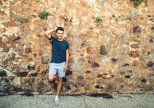 man with arm crossed smiling against the wall