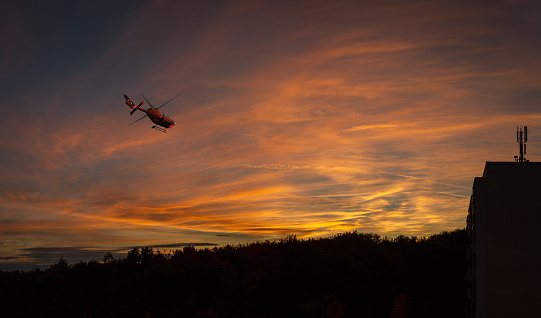 Wide panoramic view of an helicopter flying over the city during a dramatic sky sunset.