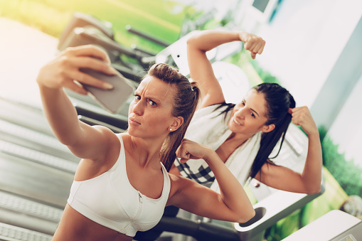 Funny female friends taking selfie after workout on the beach.