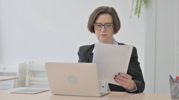 istock Old Businesswoman Working on Laptop and Documents 1470522515