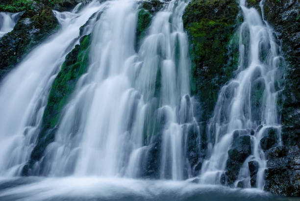 istock Beautiful mountain rainforest waterfall with fast flowing water and rocks, long exposure. Natural seasonal travel outdoor background with sun shining. Stream waterfall on rocks in the forest 1470523508
