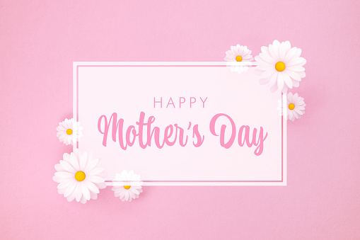 Happy Mother's Day message and white daisies on pink background. Horizontal composition with copy space. Happy Mother's Day concept.