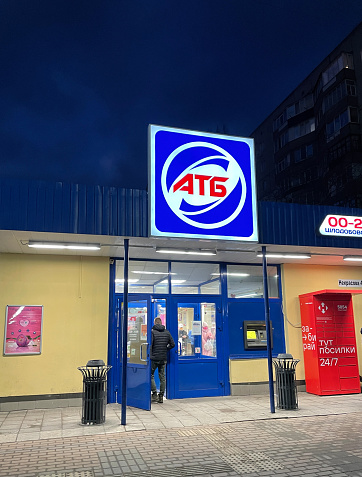 Bila Tserkva, Ukraine - February 12, 2022: 24-hour ATB supermarket at night. To the right of the entrance is the Nova Poshta parcel locker.