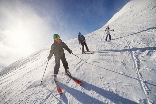 Mother and two teenage kids are skiing together in mountains on a sunny winter day. 
Canon R5