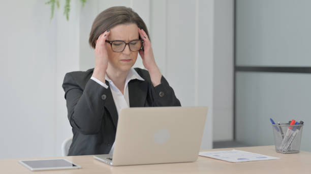 istock Old Businesswoman having Headache while Working on Laptop 1470526932