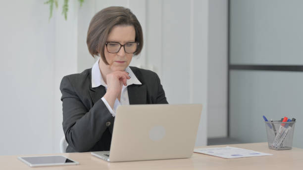 istock Old Businesswoman Thinking while Working on Laptop 1470527030