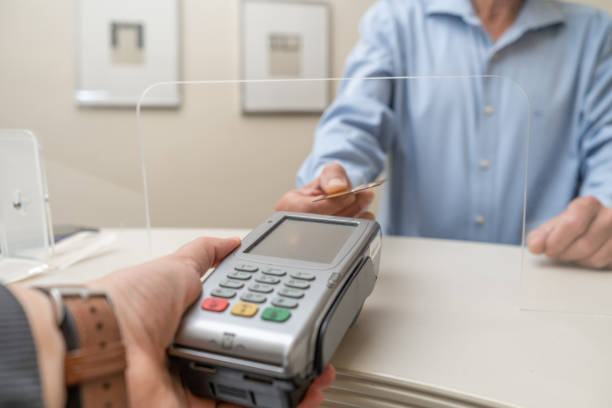 hombre adulto pagando por la visita en el consultorio del dentista en la clínica médica con tarjeta - healthcare and medicine receptionist paying credit card fotografías e imágenes de stock