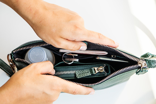 Female hands open a green handbag and show the bag inside, business life concept