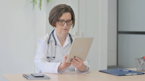 istock Old Female Doctor Browsing Tablet in Clinic 1470528289