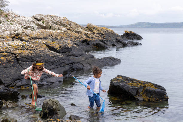 Children playing with the waves on the sea or ocean coast during a family vacation