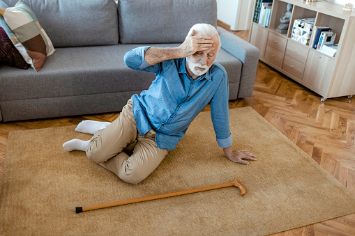Senior Man With Walking Stick Lying on Carpet at Home. Faint, Stroke, Accident or Other Health Problem, Healthcare and Medical Concept