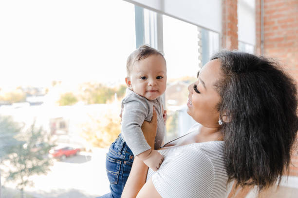 istock Cheerful baby boy held by mom looks at camera 1470530483