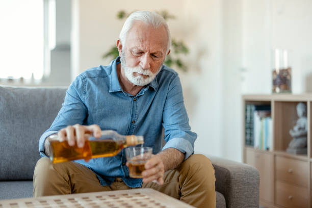 verzweifelter älterer mann, der allein nach hause trinkt - men senior adult serious depression stock-fotos und bilder