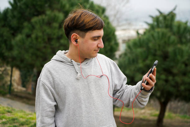 istock Man using phone with headphones walking in the city 1470530655