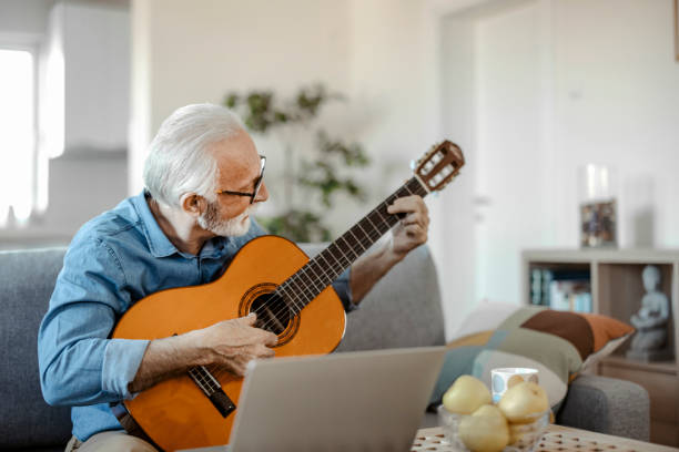 istock Elderly man playing guitar and watching online lessons 1470532078