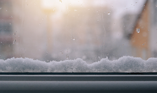 Frosted window with snow outside with sunrise background