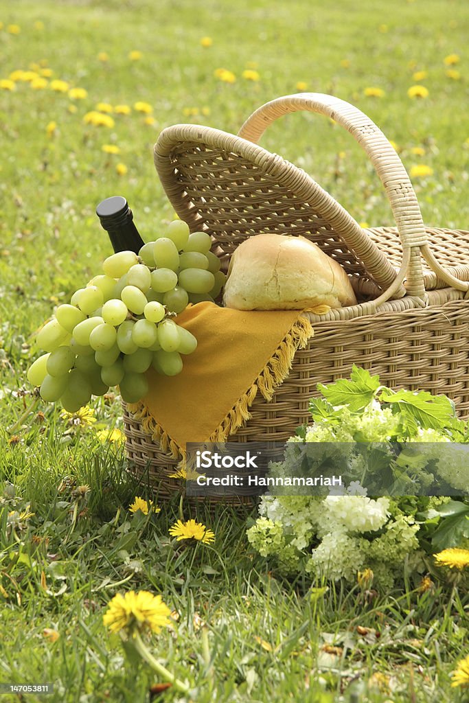 Picnic Picnic basket with bread, wine, grapes and flowers.  Wildflower Stock Photo