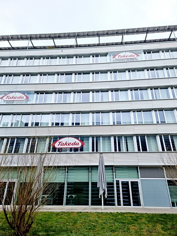 Takeda Pharmaceutical Company headquarters in switzerland. The image shows the Takeda office building in Zurich City captured during a cloudy day.