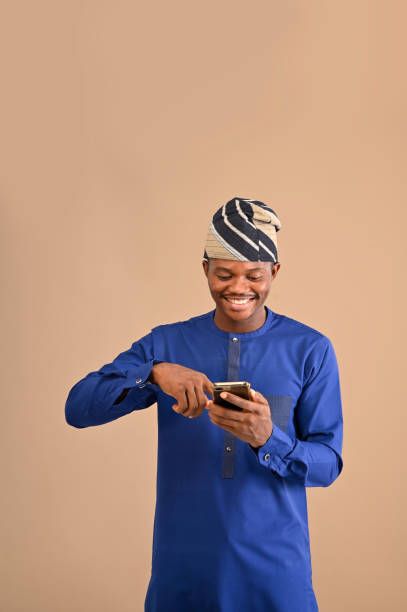 istock African businessman scrolling through his smartphone while standing on an isolated brown background 1470540045