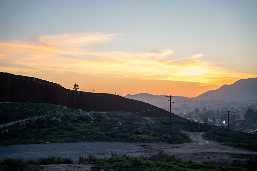 International Border Wall Between Tecate California and Tecate Mexico Near Tijuana Baja California Norte at Dusk Under Stunning Sunset with View of the City From the USA, Aerial View of the International Border Between Mexico and The USA, Drone View of the International Border Between Mexico and The United States