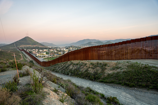 International Border Wall Between Tecate California and Tecate Mexico Near Tijuana Baja California Norte at Dusk Under Stunning Sunset with View of the City From the USA, Aerial View of the International Border Between Mexico and The USA, Drone View of the International Border Between Mexico and The United States