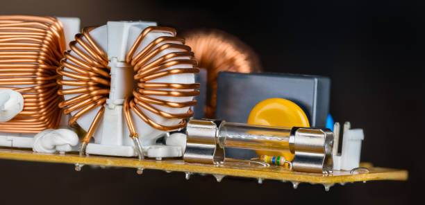 istock Glass electric fuse or toroid coils with copper wire winding in hovering printed circuit board on a black background 1470541892