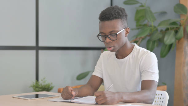 istock Young African Man Writing Letter in Office 1470542350