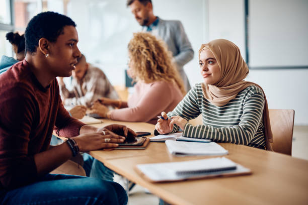 istock Muslim student and her African American classmate communicating  while learning in the classroom. 1470543940