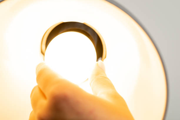 istock Female hand changes light bulb in a lamp, close up 1470545290