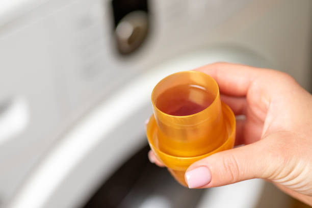 Female hand holding light brown bottle cap with liquid soap, close up