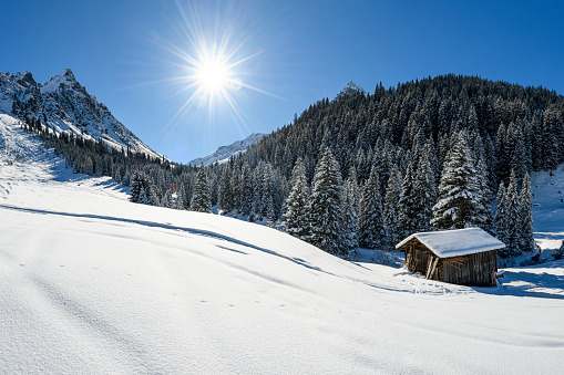 Winter landscape with an old hut, snowcapped mountains and a ski slope in the ski-resort Gargellen