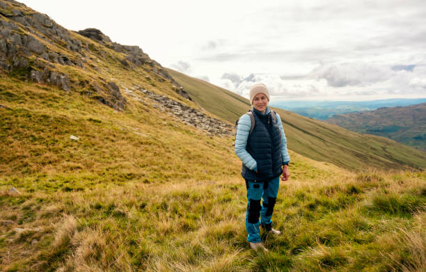 женщина, достигающая места назначения и на вершине горы на фоне облачного голубого неба в осенний день путешествия концепция образа жизни � - english lake district orienteering hiking mountain стоковые фото и изображения