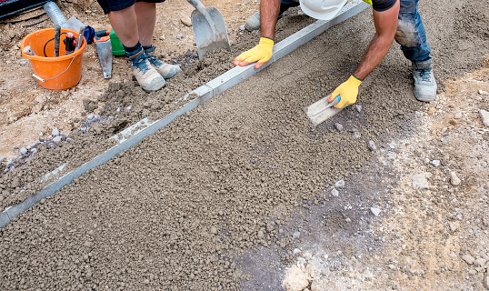 Builder placing edging kerbs on semi-dry concrete