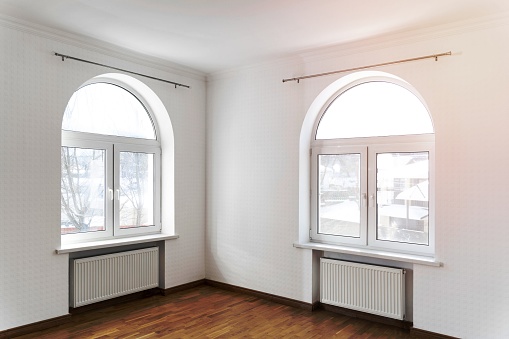 Empty room, possibly an office, modern bright white, renovated, with grey carpet flooring and white walls. Two ceiling windows and lots of natural light.