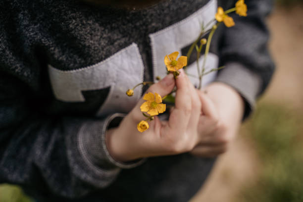 little boy holding yellow flowers in his hands. selective focus. nature.
