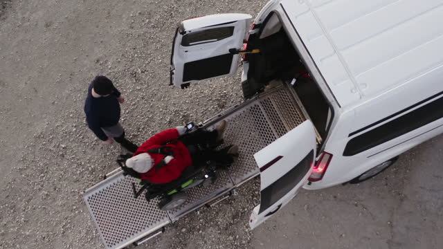 AERIAL Assisting Accessibility: Drone Captures Top-Down View of Brother Helping Sister in Wheelchair into Van