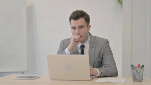 istock Young Businessman Coughing while Working on Laptop 1470555007